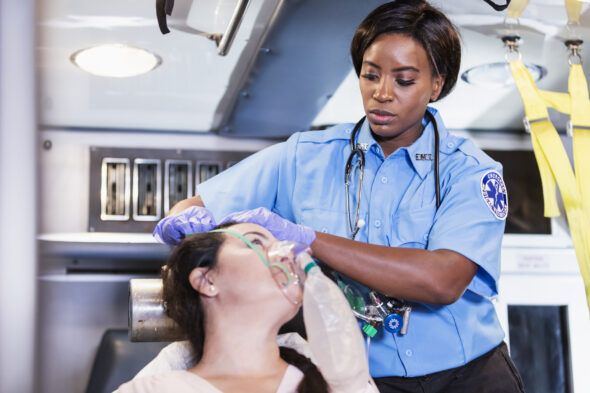 Paramedic helping Hispanic woman in ambulance
